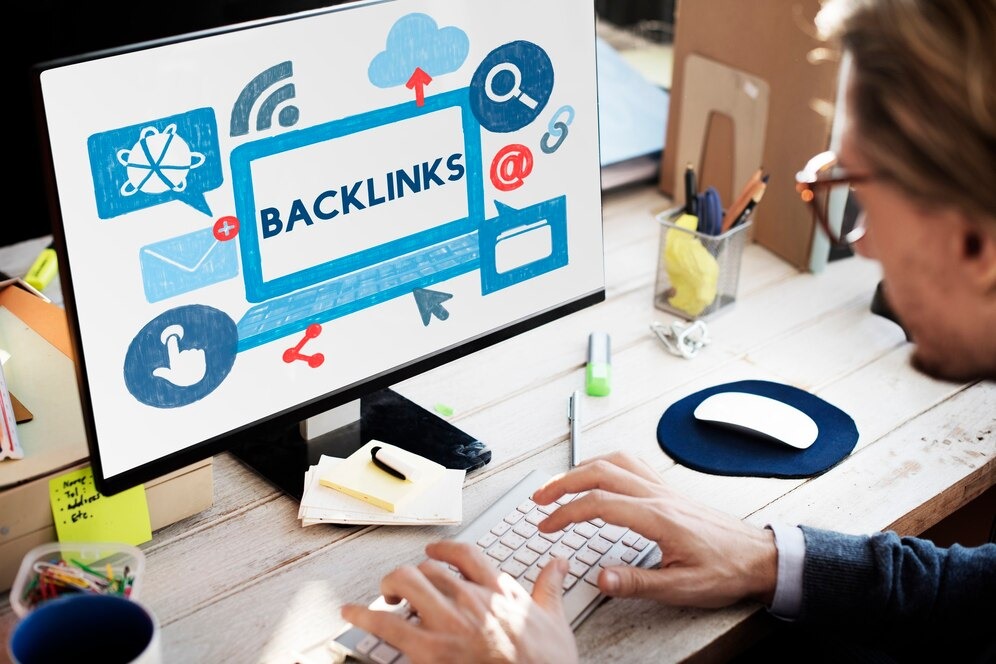 Person working on a computer with a screen displaying the word 'BACKLINKS' along with digital icons, suggesting the concept of SEO and link-building strategies.